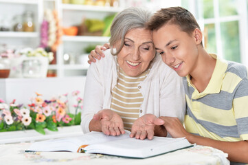 Portrait of grandmother and boy reading together at home