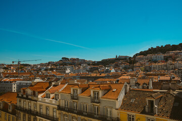 Fototapeta na wymiar Lisbon skyline rooftop view on a sunny summer day with traditonal orange rooftops of the Alfama district with sea visible in the landscape