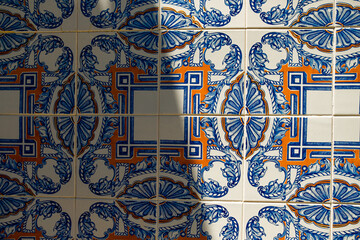 Traditional portugal tiles in blue and orange on white azulejo. Close up of colorful portuguese art and architecture symbol with natural light