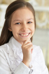 Close up portrait of emotional little girl in white blouse posing at home