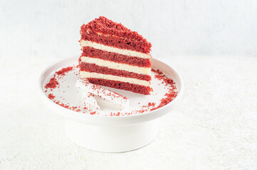 Red velvet cake. Piece on a white plate. Decorated with crumb and marshmallows. Light background.