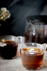There is a teapot and two cups of black tea on the table