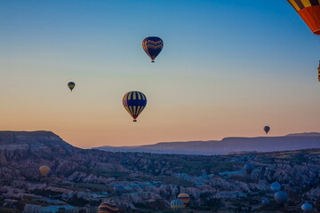 Hot air balloons flying over the valley at Cappadocia, Turkey. Goreme Balloon Festival. Beautiful hot air balloons take off at sunrise. Hot air balloons in the blue sky