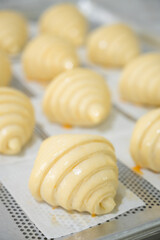 Baking classic croissants at home and brushing egg on uncooked croissants.