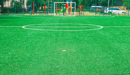 Fototapeta premium Soccer field with artificial green grass near the school. Amateur football field. Sunny summer day