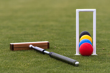 croquet mallet, wicket and colorful balls on a lawn