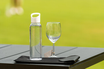 bottle of water and an empty glass on a blurred background, the concept of the need to use water