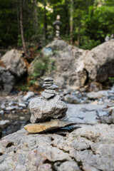 Large and small stones on background of green trees. Stone Pyramid in the mountains. Summer day.