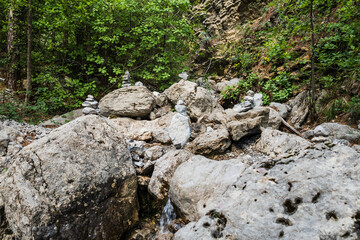 Large and small stones on background of green trees. Stone Pyramid in the mountains. Summer day.