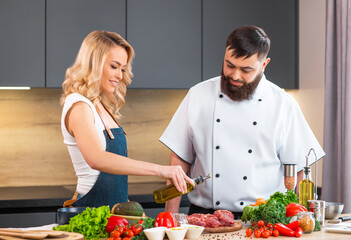 Young woman and man prepare food and host a cooking show. The bloggers stream from modern kitchen. Healthy food preparation.