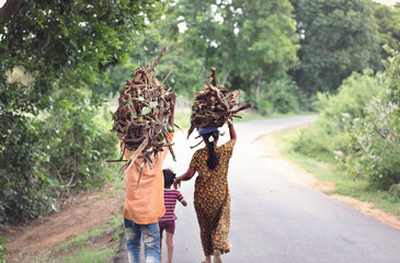 Mother and son carrying firewood on road