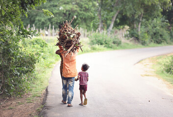 Mother and son carrying firewood on road	
