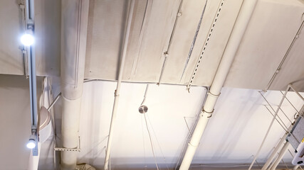 White ceiling with pipes and high-tech lamps