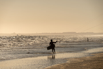 silhouette man with kitesurf kite in the sunset of the beach of huelva