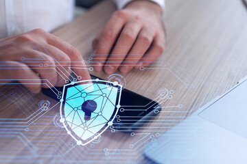 A programmer is browsing the Internet in smart phone to protect a cyber security from hacker attacks and save clients confidential data. Padlock Hologram icons over the typing hands. Formal wear.