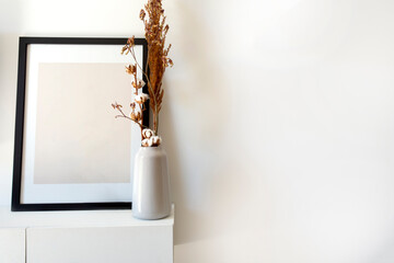 Empty wooden photo,picture frame mock-up with white vase and stylish plant near white wall on table, Copy space modern decoration interior