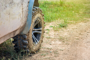 Fototapeta na wymiar wheel with disc dirty in a swamp off-road tire treads on a rough dusty road with grass close-up.