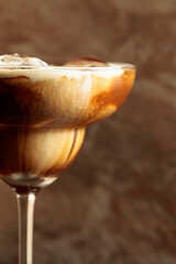 Iced coffee with natural ice and cream on a brown background.
