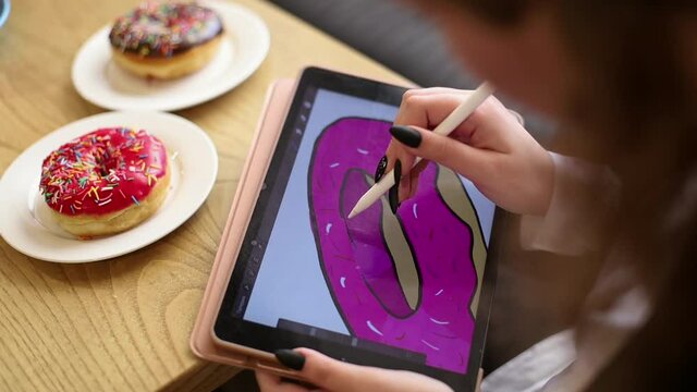 A woman's hand draws a doughnut on an electronic tablet
