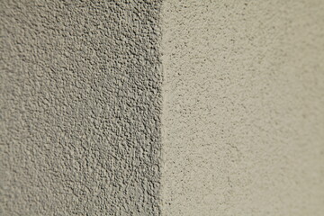 Wall texture, background. Structural plaster, uneven surface. The corner of a wall or building. Abstract two-component background. Rough and smooth surface. Textured coating in the cladding 