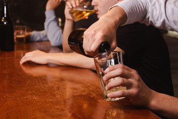 Take detail of a man carrying beer in his glass with his friends.