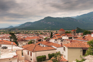 Obraz premium Rooftop view of a small European town with red tile roofs in a mountain valley under an overcast sky, Kalambaka, Meteora, Greece