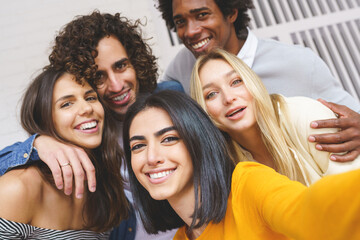 Obraz premium Multi-ethnic group of friends taking a selfie together while having fun outdoors.