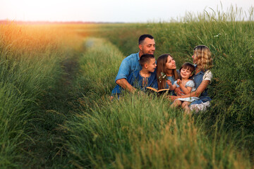 young family with children reading the Bible in nature