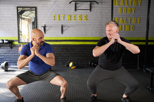 Personal trainer and Mature man, squat exercise