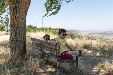 Two children sitting in a field gazebo looking out at nature