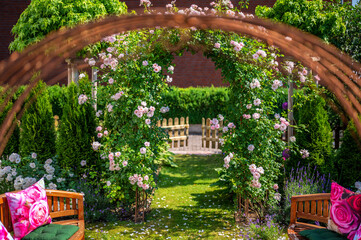Liebevoll gestalteter Garten mit gemütlicher Bank und Rosenbogen
