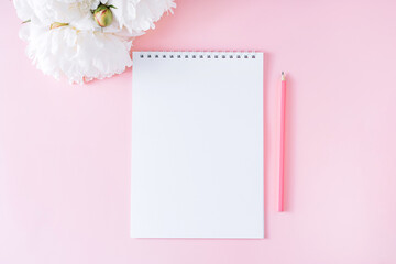 Blank notepad with pencil on pink background