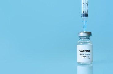 Vaccine in a bottle with a syringe on a blue background.The concept of medicine, healthcare and science.Coronavirus vaccine.Copy space for text.Banner