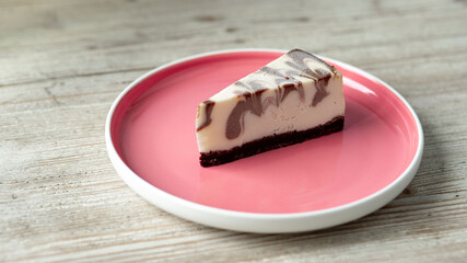 mixed chocolate frozen cheesecake on a pink plate on a wooden table