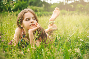 Naklejka na ściany i meble attractive teenage girl lies on the grass in a clearing on a sunny day