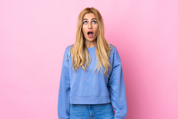 Young Uruguayan blonde woman over isolated pink background looking up and with surprised expression