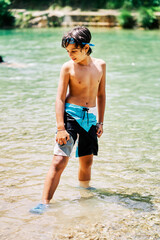 Caucasian boy in swimming trunks and goggles diving in river water in summer