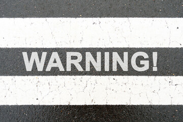 On the asphalt between the white dividing stripes the inscription - WARNING