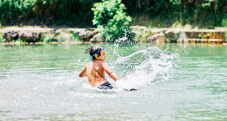 Caucasian boy in swimsuit playing with river water in summer