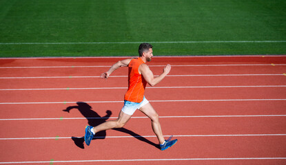 energetic athletic muscular man runner running on racetrack at outdoor stadium, challenge