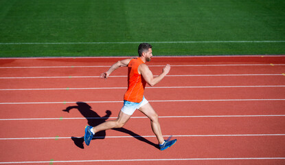 Obraz premium energetic athletic muscular man runner running on racetrack at outdoor stadium, challenge
