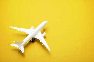 White model of passenger plane on yellow background , travel concept. Traveling by plane