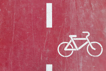 Red bike path is marked with a white painted bicycle sign, top view.