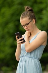 Teen girl with a mobile phone in the park.