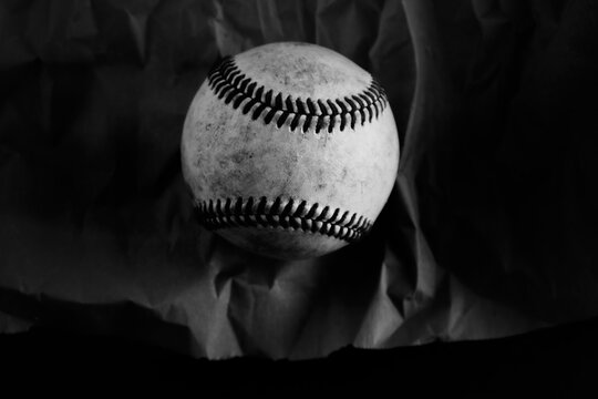 Dark moody baseball ball on texture black and white background.