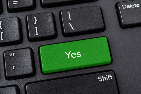 Keyboard with Yes button. Green key with Yes words on a black desktop computer keyboard. Confirm, verify, agree the terms and and accept the rules concepts. Keypad enter button with message.