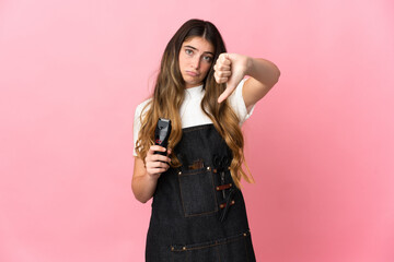 Young hairdresser woman isolated on pink background showing thumb down with negative expression