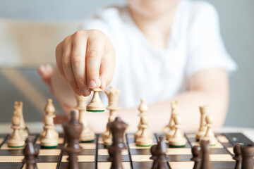 Close-up of a chess piece in the hands of a child. Pawn move. Game of chess. Chess tournaments and schools. Leisure for children