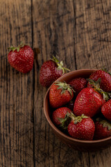 rustic red strawberry at bowl on a wooden table top. above view