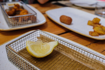 Lemon slice served on a plate with fried food
